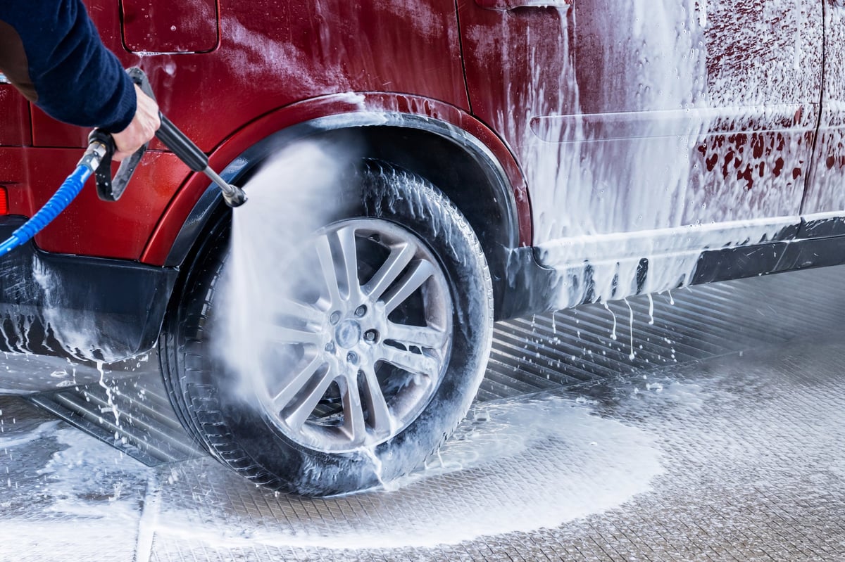 Washing red car in hand car wash. Lots of foam on car and tire.